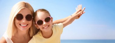 Anne ve kızı sahilde, mesaj için yer var. Pankart tasarımı