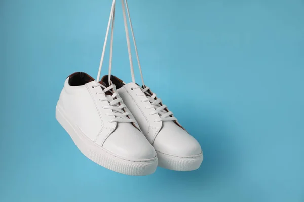 Ζεύγος Από Κομψά Λευκά Sneakers Που Κρέμονται Γαλάζιο Φόντο Χώρος — Φωτογραφία Αρχείου