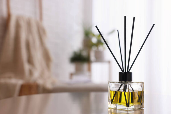 Reed diffuser on white table indoors. Space for text