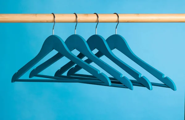 Bright Clothes Hangers Wooden Rail Light Blue Background — Stock fotografie