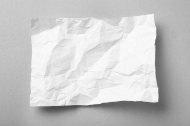 Gri arkaplan üzerine beyaz buruşuk kağıt yaprağı, üst görünüm