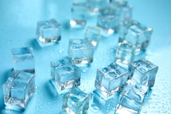 Ice cubes and water drops on turquoise background. Ingredient for refreshing drink