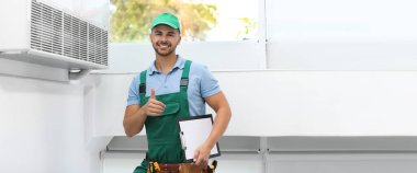Modern klimanın yanında panosu olan profesyonel bir teknisyen. Kapalı mekanda mesaj için yer var. Pankart tasarımı