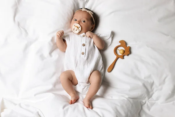 Niedliches Kleines Baby Mit Schnuller Und Rassel Auf Dem Bett — Stockfoto