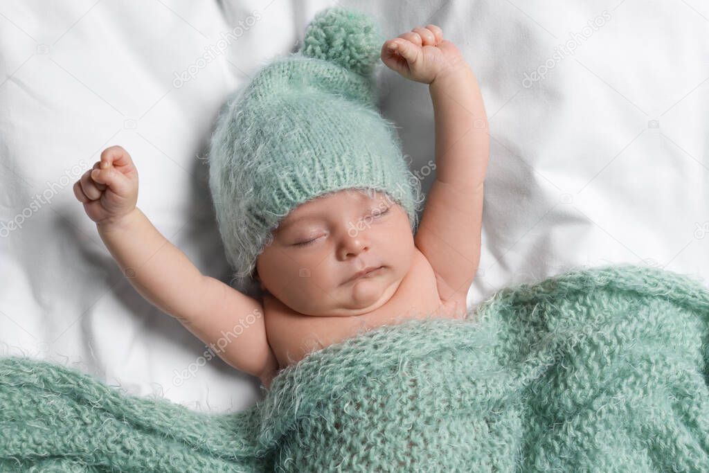 Cute little baby sleeping under knitted plaid in bed, top view