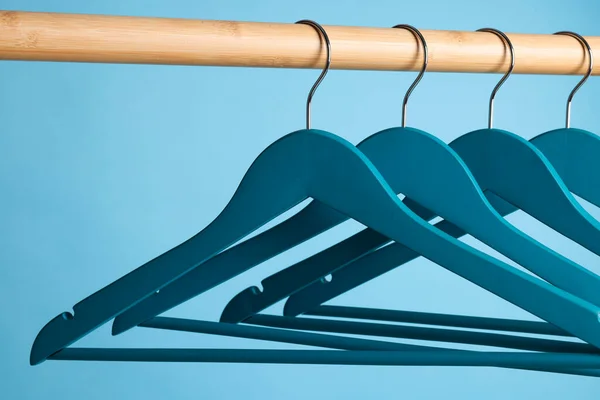 Bright Clothes Hangers Wooden Rail Light Blue Background Closeup — 图库照片