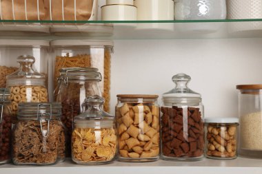 Glass containers with different breakfast cereals and other products on shelves