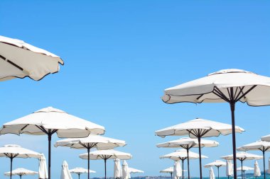 Beautiful white beach umbrellas against blue sky