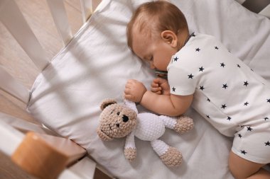 Emziği ve oyuncağı olan sevimli bir bebek. Evin içinde, yukarıda uyuyor.