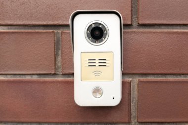 Kırmızı tuğlalı duvarda kamera olan modern dahili telefon.