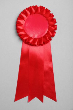 Red award ribbon on grey background, top view