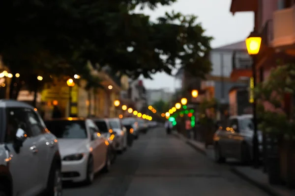 Blurred view of city street with parked cars in evening