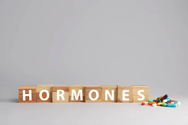 Word Hormones Made Wooden Cubes Pills Grey Background Space Text — Stockfoto