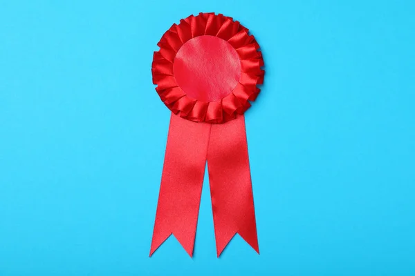 Red award ribbon on turquoise background, top view