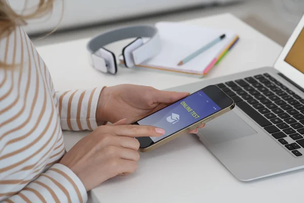 Woman taking online test on smartphone at desk indoors, closeup