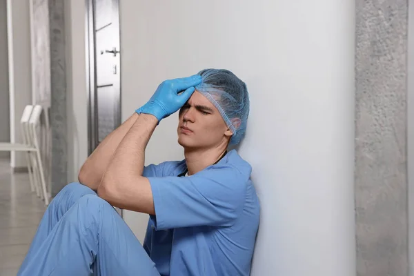 Erschöpfter Arzt Sitzt Neben Grauer Wand Krankenhausflur — Stockfoto