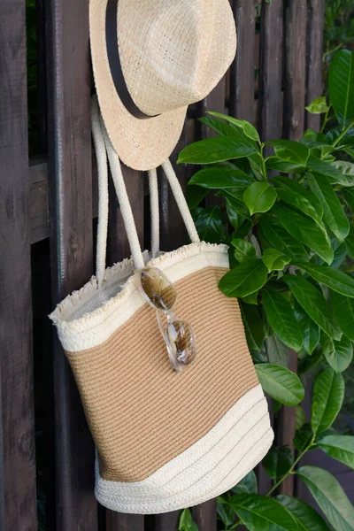 Stylish Bag Hat Sunglasses Hanging Wooden Fence Outdoors Beach Accessories — Stockfoto