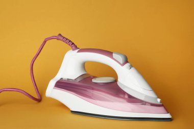 Turuncu arka planda modern bir ütü. Ev aletleri