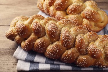 Ahşap masada susam tohumlu ev yapımı örülmüş ekmek, yakın plan. Şabat için Challah