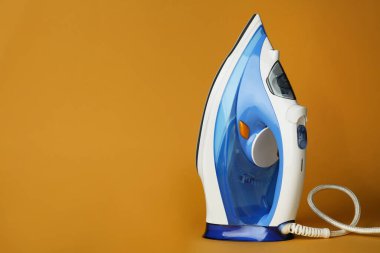 Turuncu arka planda modern bir ütü, metin için boşluk. Ev aletleri