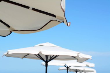 Beautiful white beach umbrellas against blue sky