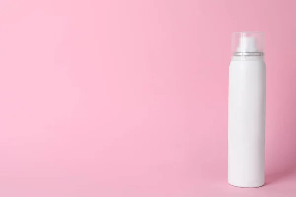 Bottle of dry shampoo on pink background, space for text