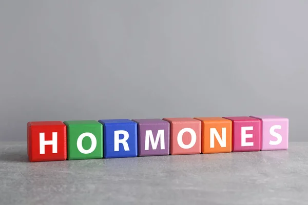 Slovo Hormones Vyrobeno Barevných Kostek Šedém Stole — Stock fotografie