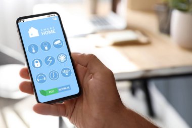 Smart Home uygulamasını kullanan adam cep telefonunu kapalı alanda kullanıyor.