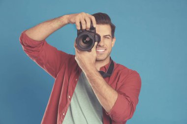 Mavi arka planda kamera olan profesyonel fotoğrafçı.