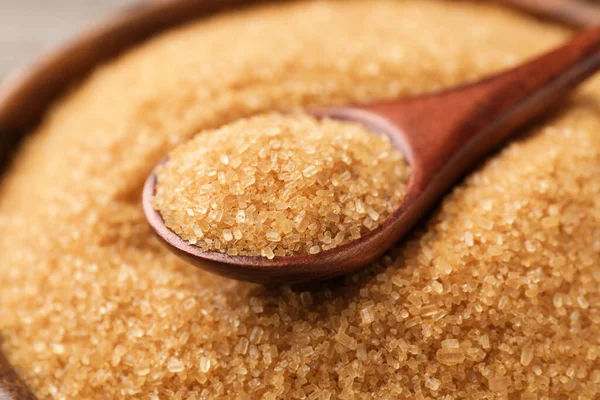 Wooden bowl and spoon with brown sugar, closeup