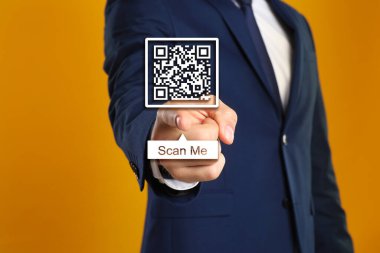 Man pointing at illustration of QR code on orange background, closeup