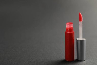 Koyu arkaplanda aplikatörü olan kırmızı dudak parlatıcı. Metin için boşluk