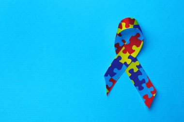 World Autism Awareness Day. Colorful puzzle ribbon on turquoise background, top view with space for text