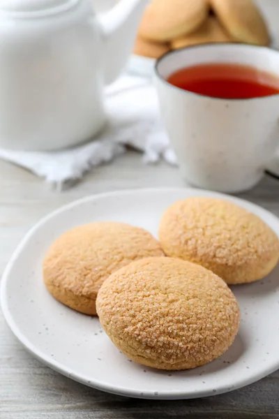 Delicious sugar cookies and cup of tea on white table, closeup