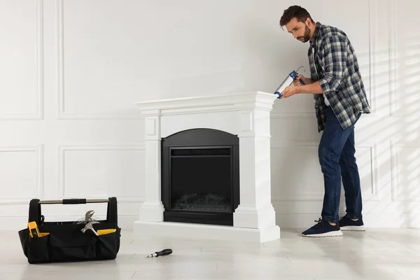 Man Sealing Electric Fireplace Caulk White Wall Room — Stockfoto