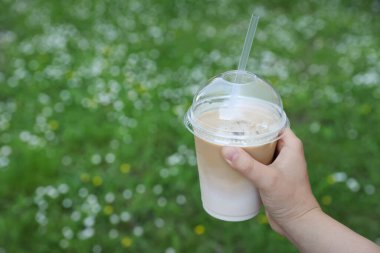 Elinde plastik bardakta lezzetli buzlu kahve tutan bir kadın, yakın plan. Metin için boşluk