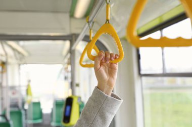 Woman holding handgrip handle in public transport, closeup clipart