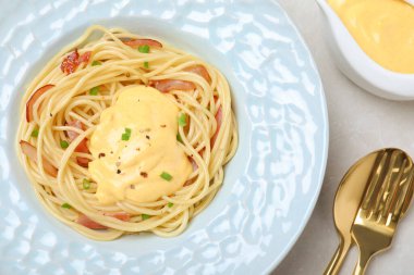 Açık gri masada servis edilen et ve peynir soslu leziz spagetti.