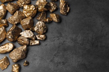 Pile of gold nuggets on grey table, flat lay. Space for text