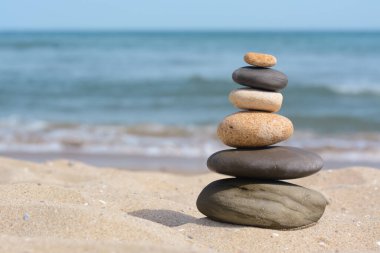 Stack of stones on sandy beach near sea, space for text