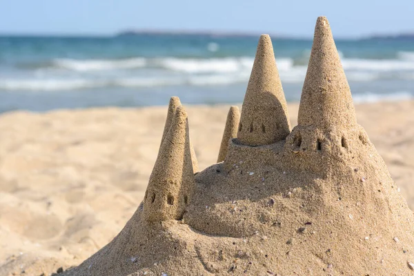 Beach with sand castle near sea on sunny day. Space for text