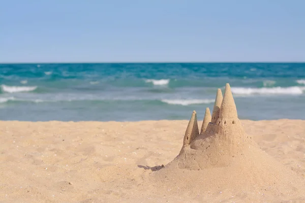 Beach with sand castle near sea on sunny day. Space for text