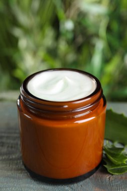 Açık mavi ahşap masada el kremi ve aloe kavanozu, yakın plan.