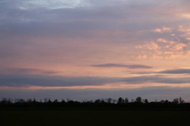 Gün batımında güzel kırsal manzaranın resmi.