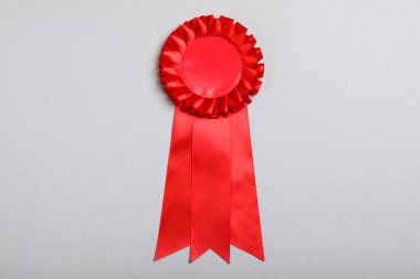 Red award ribbon on grey background, top view