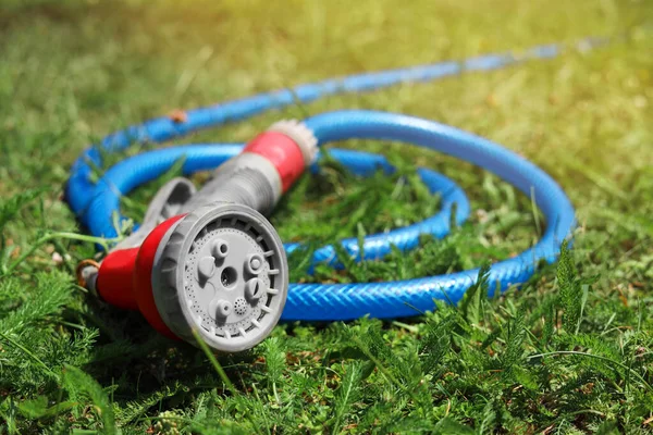 Watering hose with sprinkler on green grass outdoors, closeup. Space for text