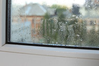 Wet window on rainy day, closeup. View from inside