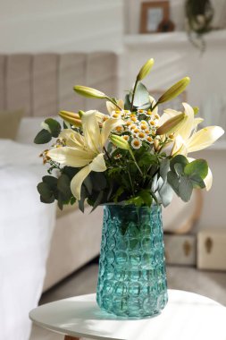 Bouquet of beautiful flowers on white table in bedroom