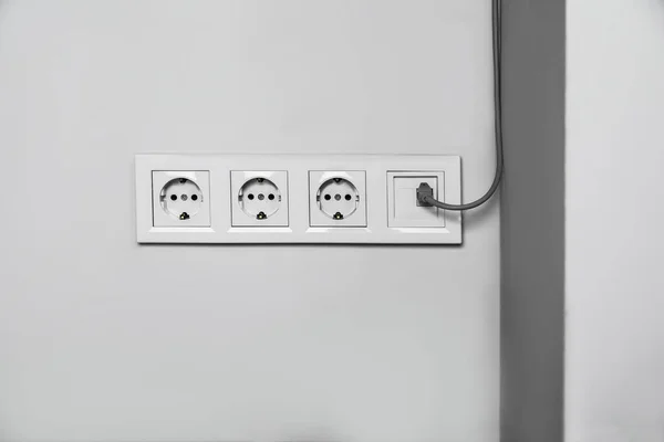 Power sockets with internet cable on white wall. Electrical supply
