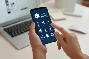 Smart Home uygulamasını kapalı mekanda cep telefonunda kullanan bir kadın.